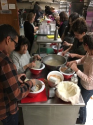 A cooking class at the Stroum JCC in Seattle made an entire meal. People in the front are grating potatoes for dumplings, while those in the back are preparing mushrooms, cabbage slaw, and making chocolate hazelnut cookies.